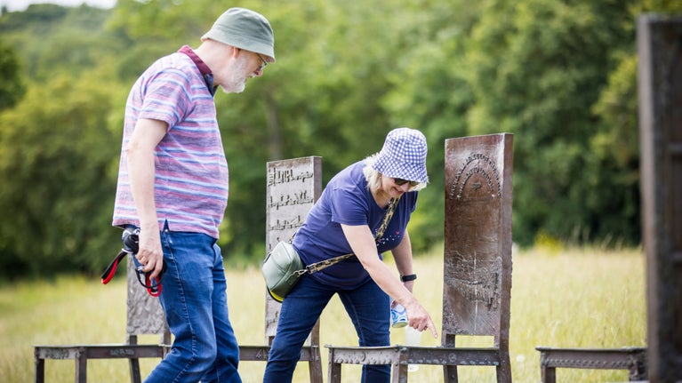 A lady taking a closer look one of the twelve chairs that form part of The Jurors art installation at Runnymede.